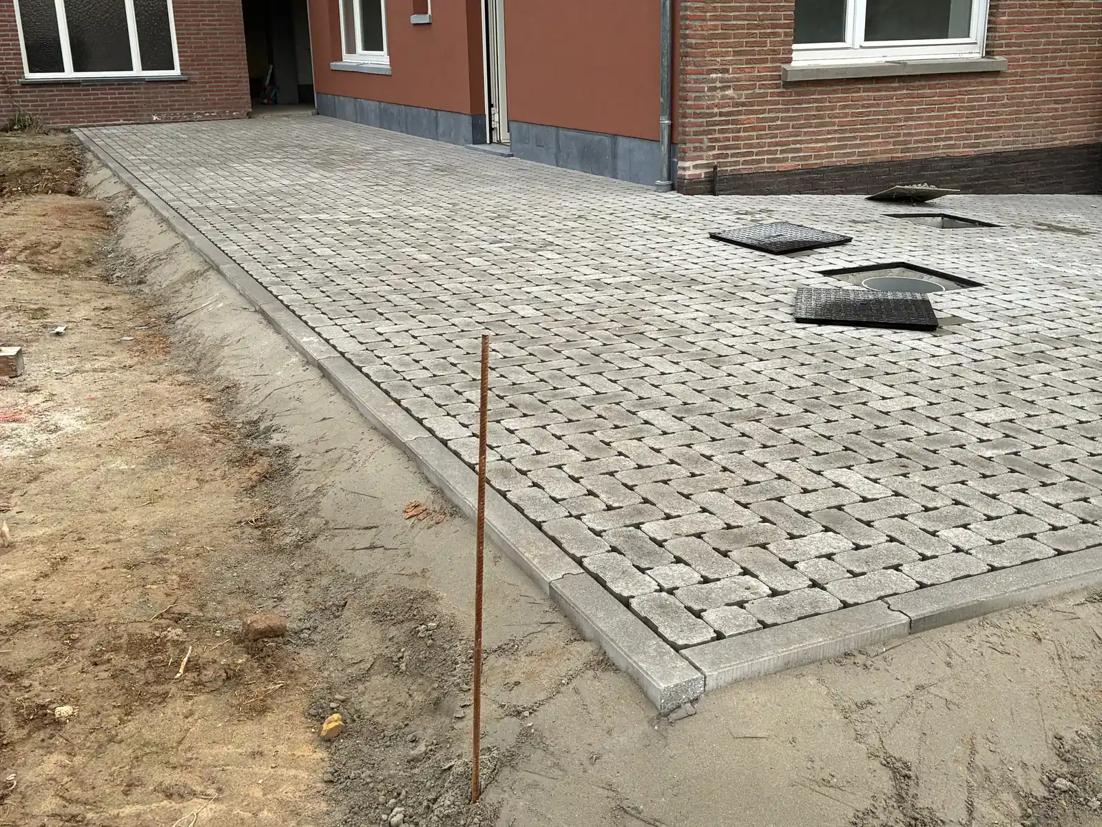 Terras in klinkers met boordstenen achter een woning, aangelegd door De Wachter & Zoon