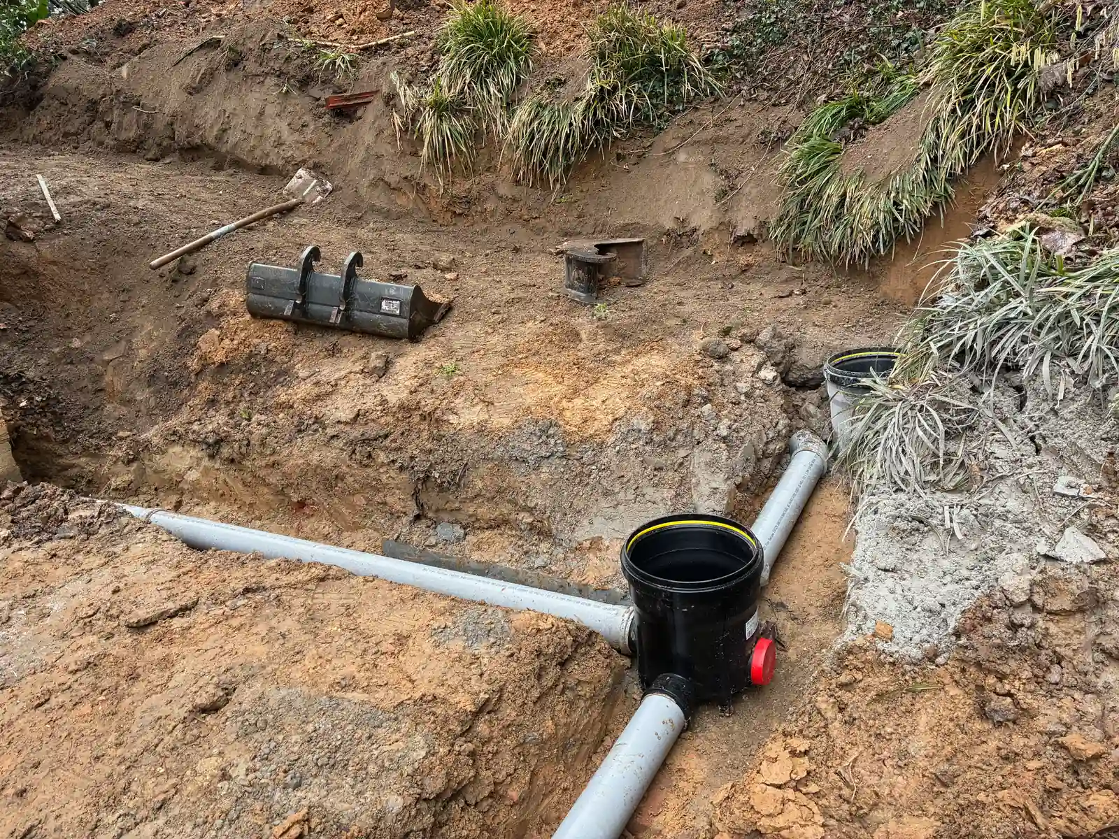 Toezichtsput met PVC-aansluitingen in een sleuf bij een woning