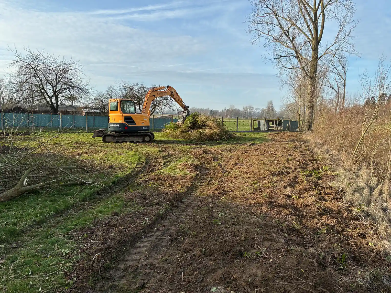 Kraan van De Wachter & Zoon bij een hoop struiken op een terrein dat vrijgemaakt wordt